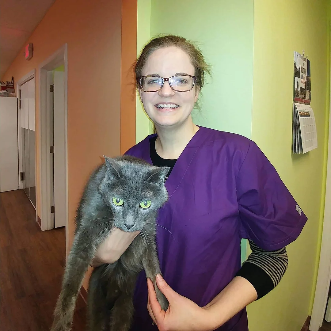 Dr. Autumn Tatro-AuBuchon Dr. Autumn Tatro-AuBuchon smiling and holding a grey cat in clinic hallway