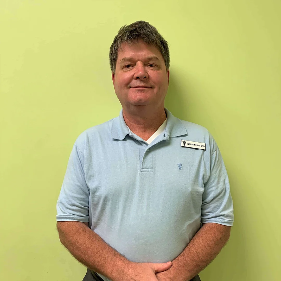 Dr. John Ring Dr. John Ring standing against a green wall in a light blue polo